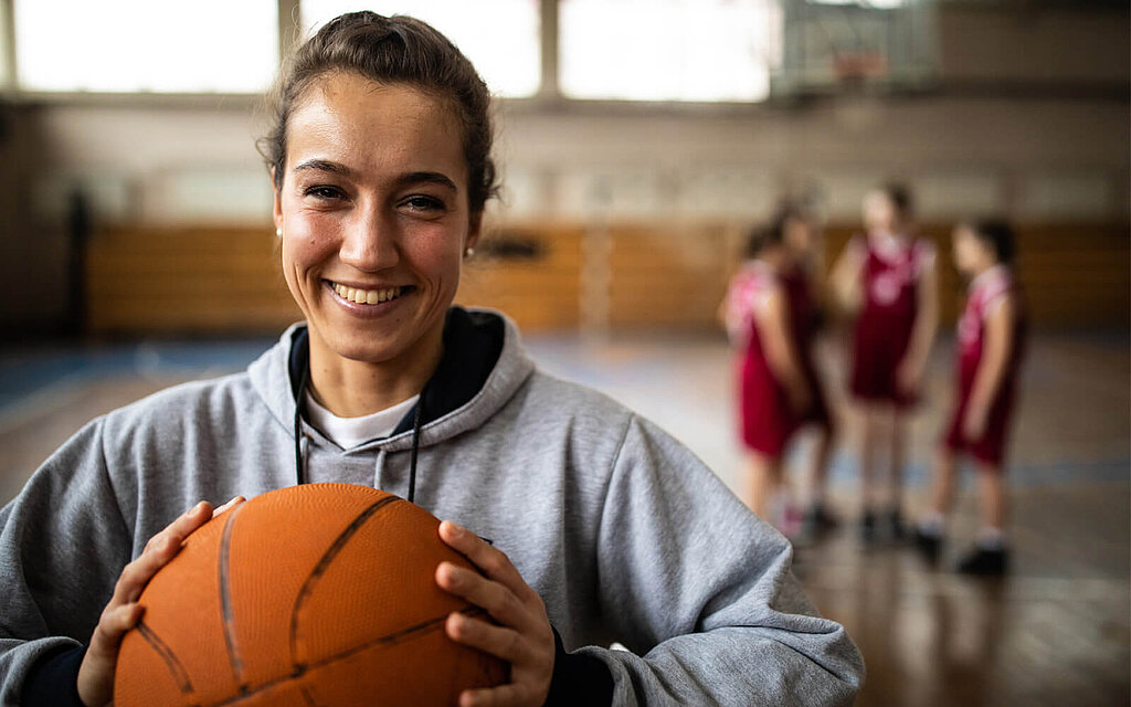 "Im Sportuntericht hält eine Basketballspielerin den Ball in den Händen. "